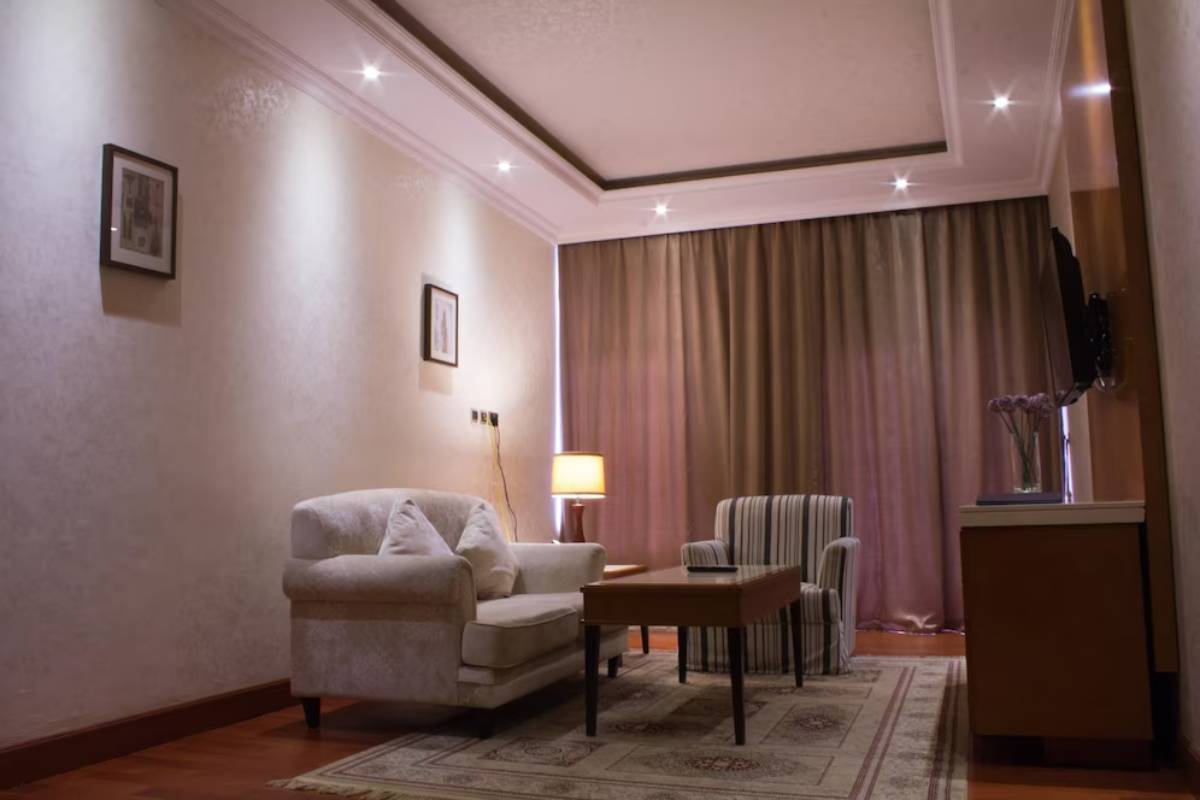 Cozy living area featuring a white couch, striped armchair, coffee table, warm lighting, and elegant curtains.