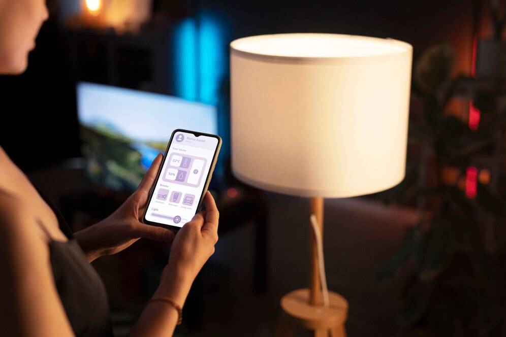 A person adjusting a smart lamp's settings using a mobile app in a cozy, dimly lit room.
