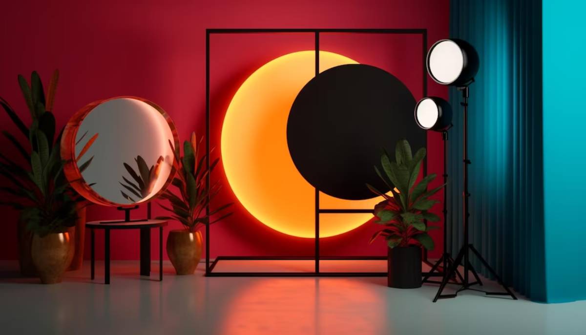 Modern interior scene featuring a circular mirror, vibrant orange and black wall art, potted plants, and studio lighting on a pink backdrop.